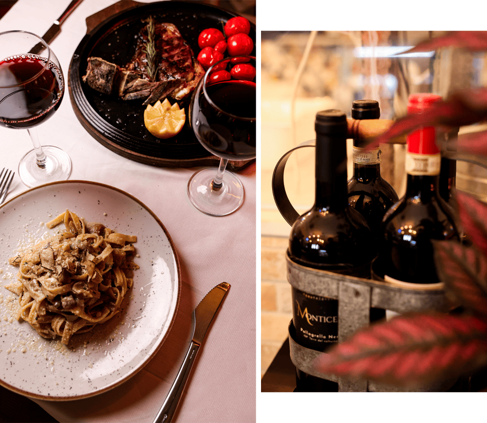 Table set with pasta, grilled meat, and bottles of red wine - Ristorante Pizzeria Mercede